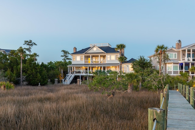 rear view of house featuring a standing seam roof, a balcony, metal roof, stairway, and a chimney