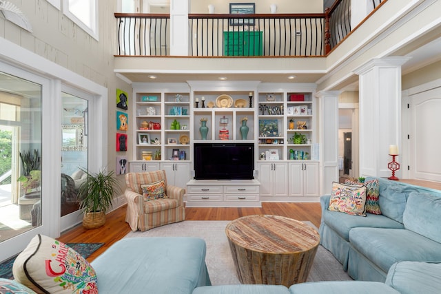 living area featuring a towering ceiling, light wood-style floors, and built in features