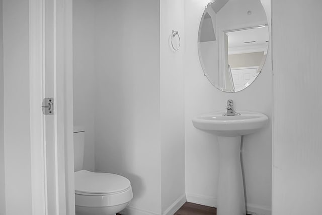 bathroom with baseboards, toilet, and a sink
