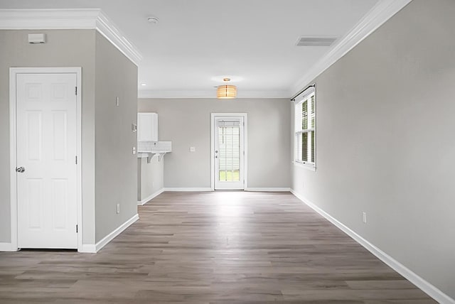 interior space featuring crown molding, visible vents, wood finished floors, and baseboards