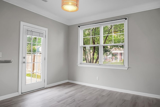 unfurnished room with baseboards, wood finished floors, crown molding, and plenty of natural light
