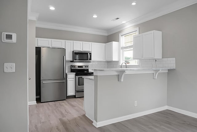 kitchen featuring appliances with stainless steel finishes, a breakfast bar, visible vents, and ornamental molding