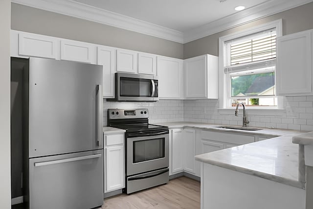 kitchen with ornamental molding, a sink, white cabinetry, and stainless steel appliances