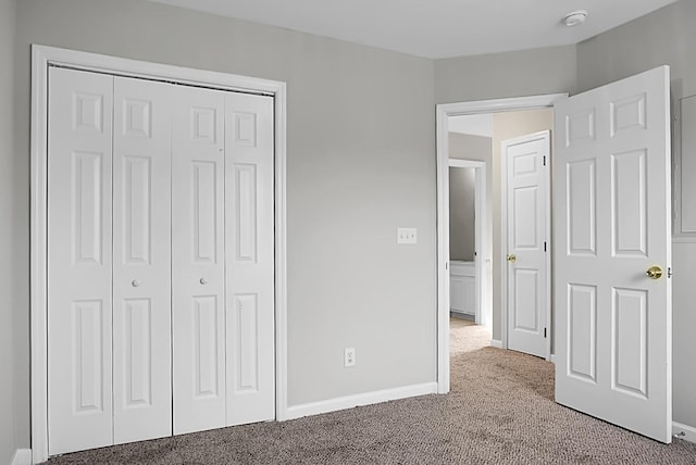 unfurnished bedroom with a closet, carpet, and baseboards