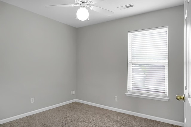 spare room with baseboards, visible vents, ceiling fan, and light colored carpet