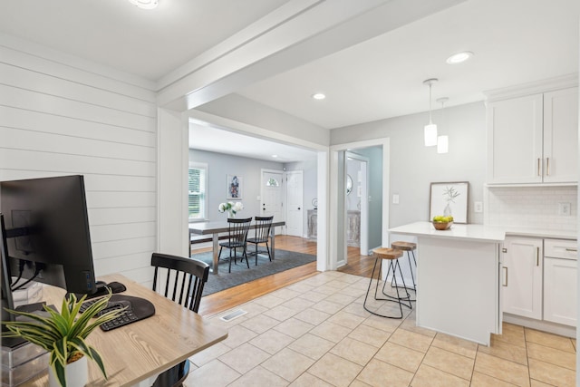 kitchen with white cabinetry, light countertops, decorative backsplash, a kitchen bar, and pendant lighting