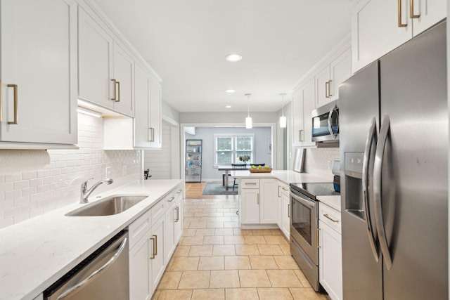 kitchen featuring decorative light fixtures, backsplash, appliances with stainless steel finishes, white cabinets, and a sink