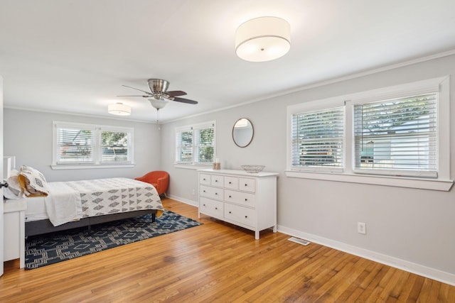 bedroom with ornamental molding, light wood finished floors, a ceiling fan, and baseboards