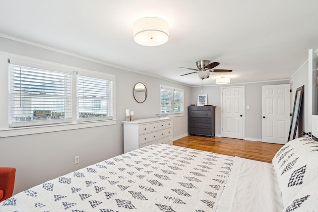 bedroom with ceiling fan, ornamental molding, wood finished floors, and baseboards