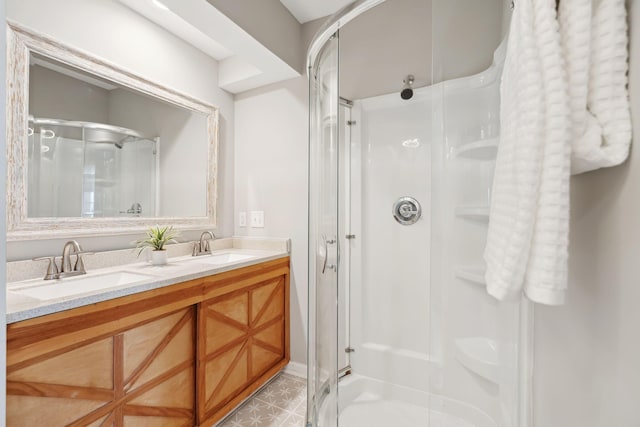 bathroom featuring double vanity, a stall shower, and a sink