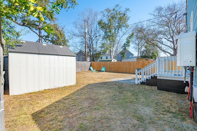 view of yard with a fenced backyard, a shed, and an outbuilding