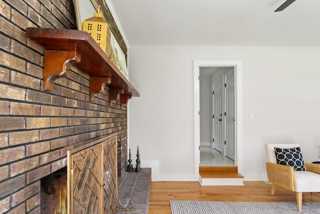 unfurnished living room with a brick fireplace, wood finished floors, and baseboards