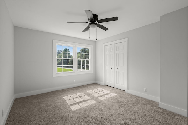 unfurnished bedroom featuring baseboards, carpet floors, a closet, and ceiling fan