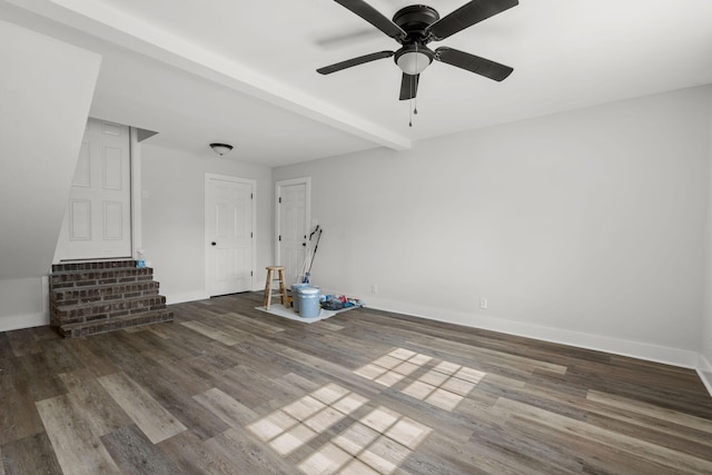 unfurnished living room featuring beamed ceiling, wood finished floors, baseboards, and ceiling fan