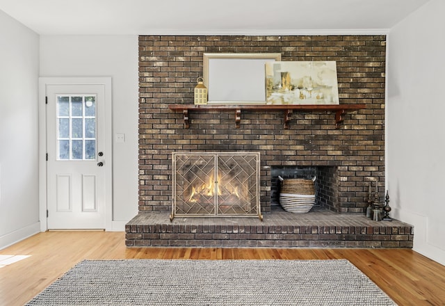 room details featuring baseboards, wood finished floors, and a fireplace