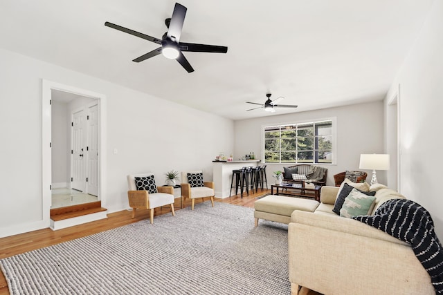 living room featuring wood finished floors, a ceiling fan, and baseboards