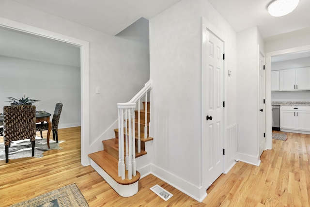 stairway with wood finished floors, visible vents, and baseboards