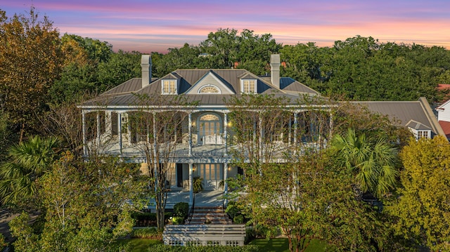 view of front of property featuring a standing seam roof, a chimney, and metal roof