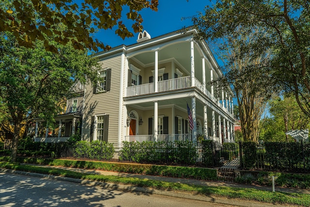 view of front facade with a balcony and a fenced front yard