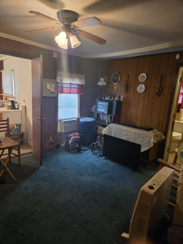 carpeted bedroom with ceiling fan, wooden walls, and ornamental molding