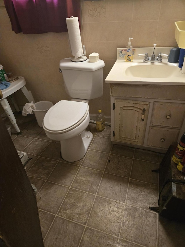 bathroom featuring tile patterned flooring, vanity, toilet, and tile walls