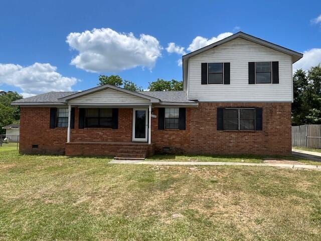 traditional-style house with brick siding, crawl space, fence, and a front lawn