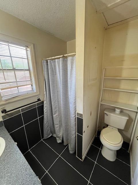 bathroom featuring a textured ceiling, a shower with shower curtain, tile patterned floors, and toilet