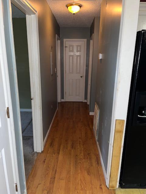 hall with baseboards and light wood finished floors