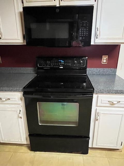 kitchen featuring white cabinetry, dark countertops, light tile patterned floors, and black appliances