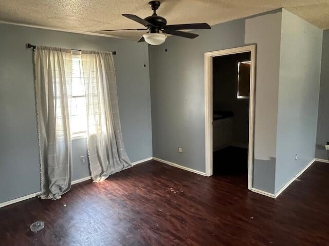 unfurnished bedroom featuring a textured ceiling, baseboards, a ceiling fan, and wood finished floors