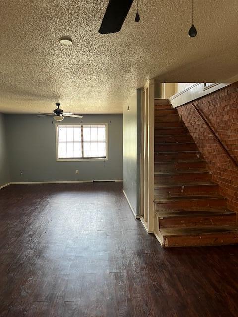 interior space featuring a textured ceiling, ceiling fan, baseboards, and stairway