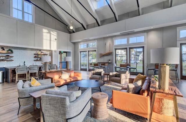 living room with beam ceiling, high vaulted ceiling, and light hardwood / wood-style flooring