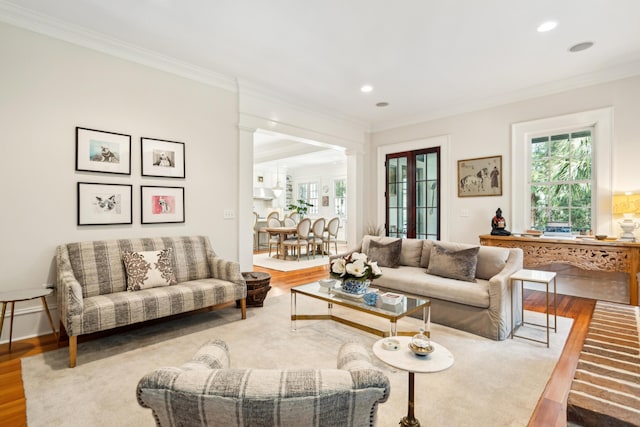 living area with ornamental molding, wood finished floors, and a healthy amount of sunlight