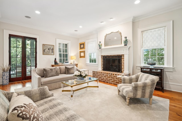 living area with a brick fireplace, recessed lighting, crown molding, and wood finished floors