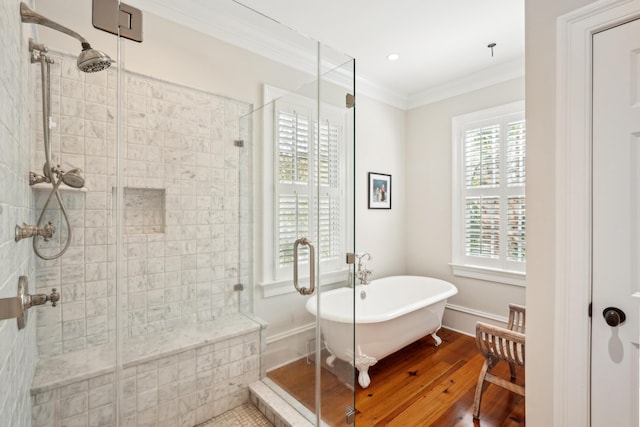 full bath with a stall shower, crown molding, wood finished floors, a soaking tub, and baseboards