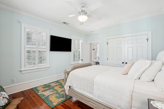 bedroom with a closet, visible vents, baseboards, ornamental molding, and wood finished floors