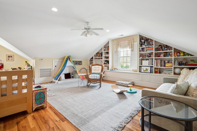 living area with wood finished floors, lofted ceiling, built in features, visible vents, and ceiling fan