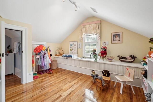 recreation room featuring rail lighting, visible vents, vaulted ceiling, and wood finished floors