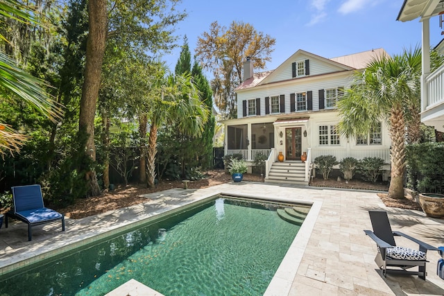 rear view of property featuring a chimney, an outdoor pool, and a patio area