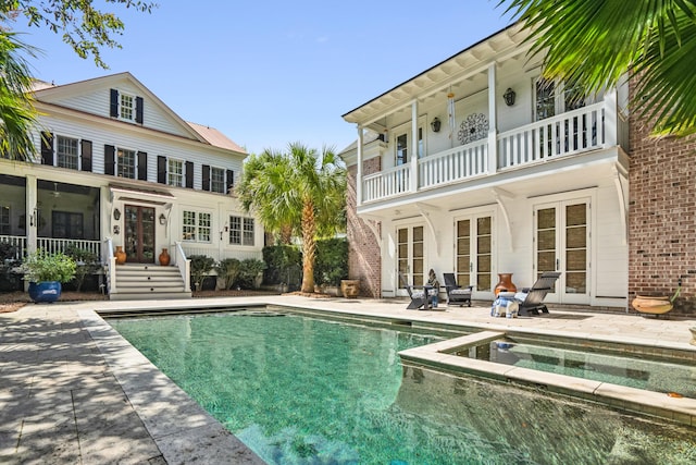 view of pool with french doors, a pool with connected hot tub, and a patio area