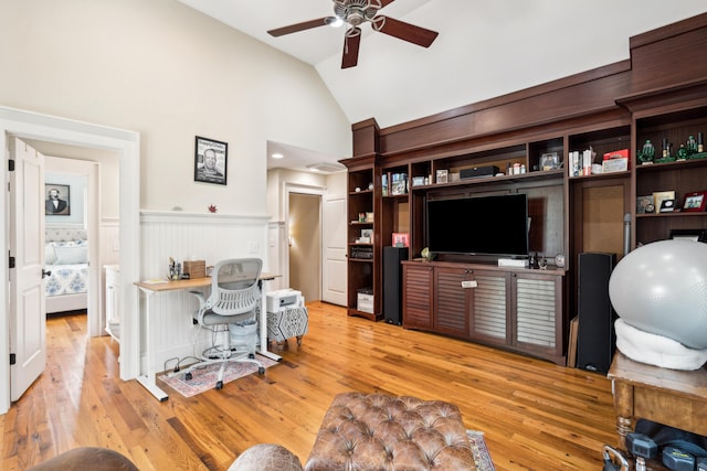 office space with a wainscoted wall, lofted ceiling, a ceiling fan, and hardwood / wood-style flooring