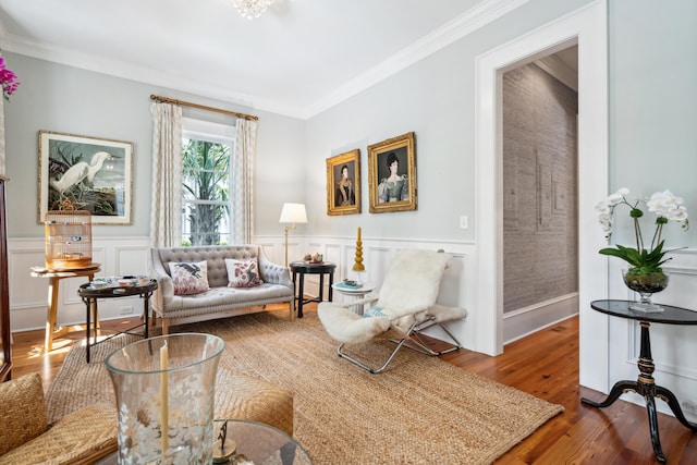 living area featuring a wainscoted wall, wood finished floors, and ornamental molding