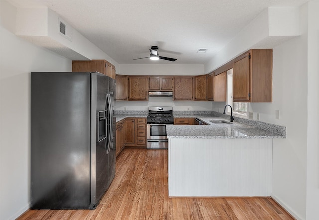 kitchen featuring sink, light hardwood / wood-style flooring, ceiling fan, appliances with stainless steel finishes, and kitchen peninsula