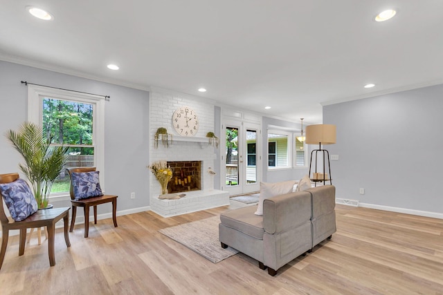 living room featuring ornamental molding, a brick fireplace, and light hardwood / wood-style flooring