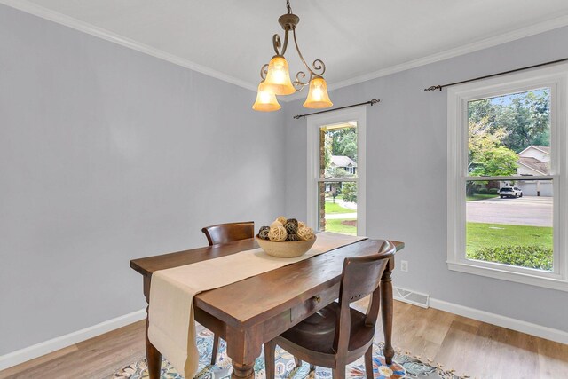 dining space featuring plenty of natural light, a chandelier, ornamental molding, and light hardwood / wood-style flooring