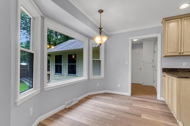 unfurnished dining area featuring light wood-type flooring, a wealth of natural light, and ornamental molding