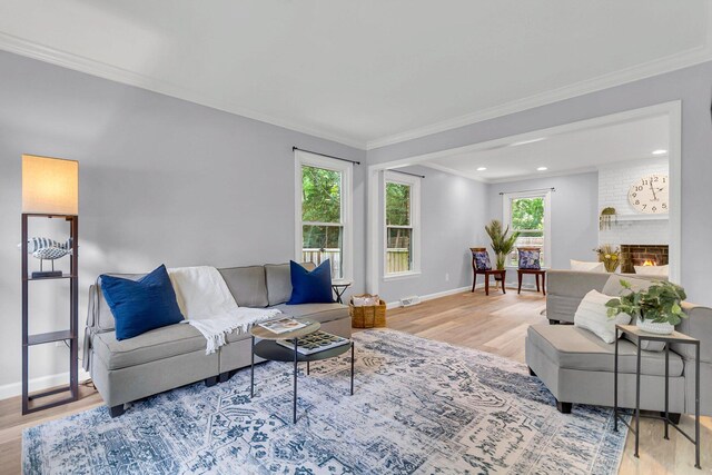 living room with ornamental molding, light wood-type flooring, and a brick fireplace