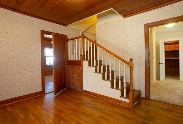 stairway featuring wood-type flooring, ornamental molding, and wooden ceiling