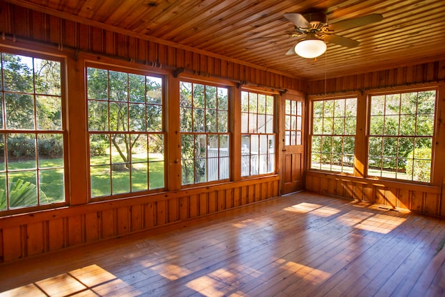 unfurnished sunroom featuring ceiling fan, a healthy amount of sunlight, and wooden ceiling