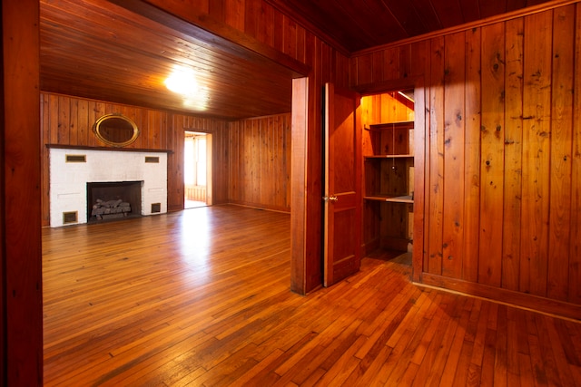 unfurnished living room with wooden walls, wood-type flooring, and wooden ceiling